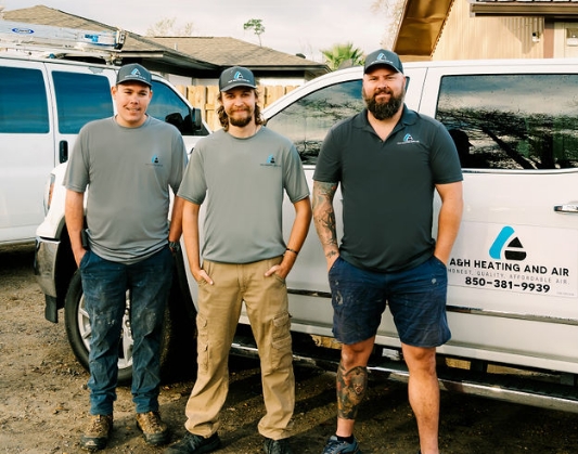 Three Panama City H V A C contractors standing against white pickup truck