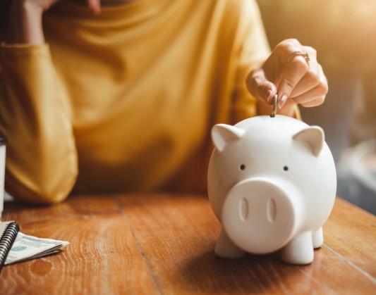 Person placing a coin inside of a piggy bank