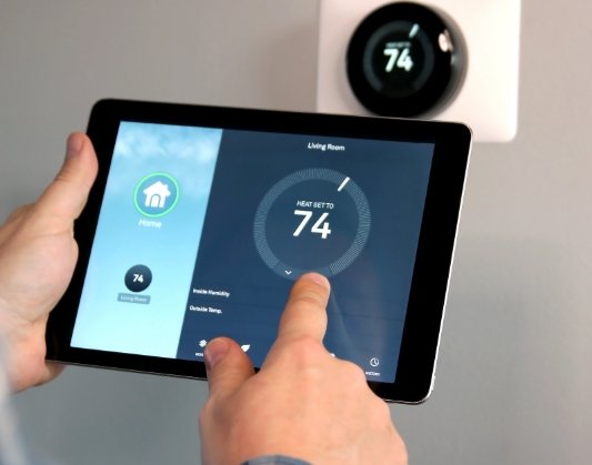 Person using a tablet to adjust their thermostat
