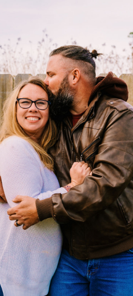 Joe holding and kissing his wife outdoors