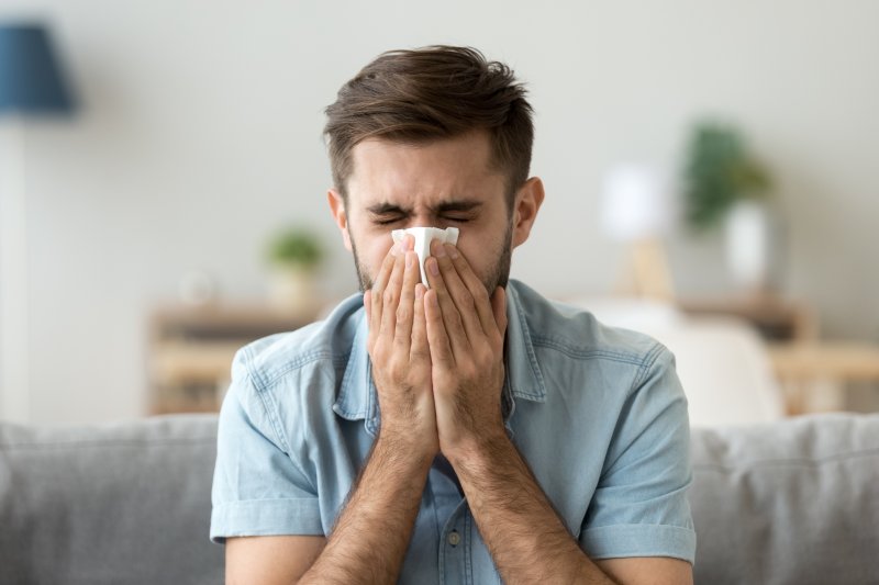 a man blowing his nose due to allergies