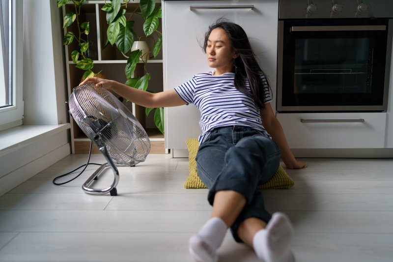 a woman sitting on the floor next to a fan