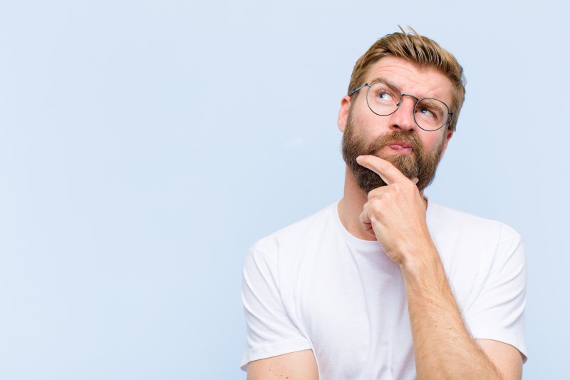 a man with glasses looking up and pondering
